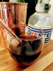 afbeelding van glas met black russian cocktail een koperen maatbeker en een fles wodka